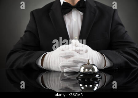 Close-up of waiter sitting at desk avec le service bell Banque D'Images