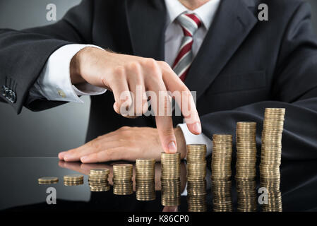 Close-up of woman's doigts marche sur pile de pièces à 24 Banque D'Images