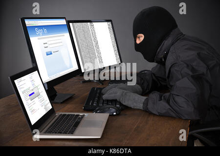 Hacker portant cagoule pirater des ordinateurs à 24 Banque D'Images