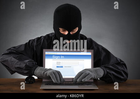 Hacker hacking compte de site de réseautage social sur laptop at desk Banque D'Images