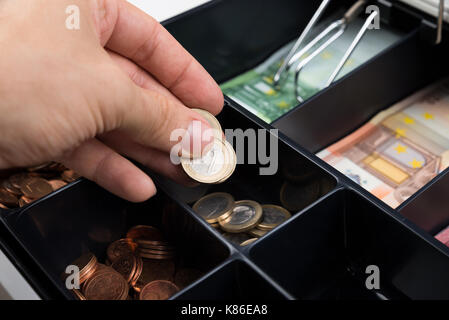 Close-up of personne mains mettre des pièces dans la caisse Banque D'Images