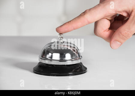 La main coupée de businessman ringing service bell on desk Banque D'Images