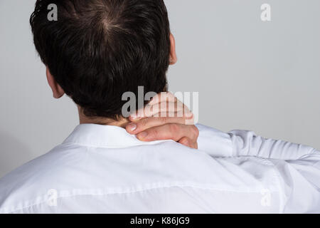 Vue arrière du businessman souffrant de douleur au cou contre fond blanc Banque D'Images