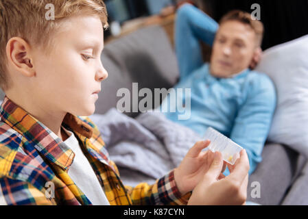 Close up of pre-teen boy holding pill organizer Banque D'Images
