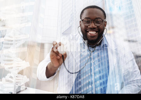 African American doctor amusé à l'aide d'écouteurs médical Banque D'Images