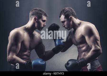 Deux boxeurs gants de boxe a rencontré des regards sur un fond sombre Banque D'Images