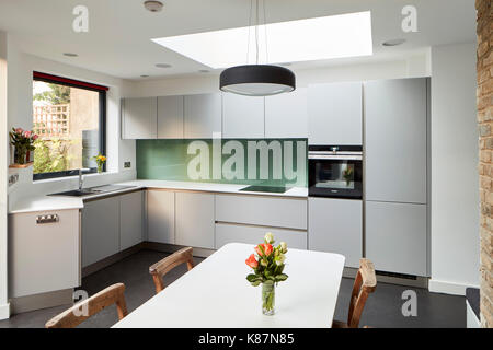 Vue d'angle de cuisine avec table à manger en premier plan. Maison privée, Londres, Royaume-Uni. Scénario : Architecte Architecture, 2016. Banque D'Images