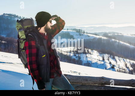 Homme barbu randonneur sur une montagne enneigée randonnée d'hiver. Banque D'Images