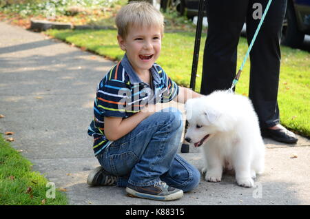 Portrait Of A Cute Heureux Et Souriant Garcon Qui Joue Avec Un Bebe Chien Spitz Japonais Photo Stock Alamy