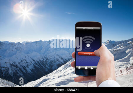 Close-up of personne part avec aucun signal wifi sur téléphone mobile dans la montagne enneigée Banque D'Images