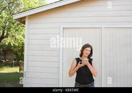 Une femme tenant un petit poussin duveteux, un bébé oiseau dans ses deux mains. Banque D'Images