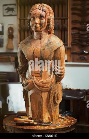 Une femme en bois sculpté de proue du navire sur un banc dans un atelier avec un motif de grain du bois, le balisage Banque D'Images