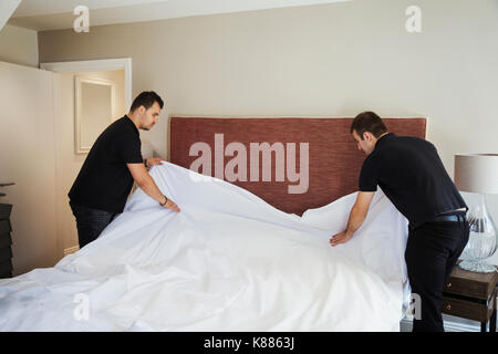 Deux hommes debout dans la chambre d'hôtel, ce qui en lit. Banque D'Images