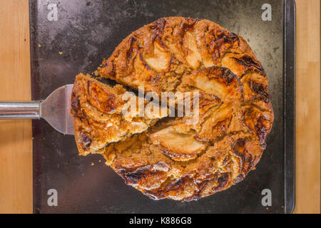 Une coupe triangulaire de gâteau aux pommes épicées, de refroidissement sur une plaque de cuisson dans une cuisine, de l'étuve. Angleterre, Royaume-Uni. Banque D'Images