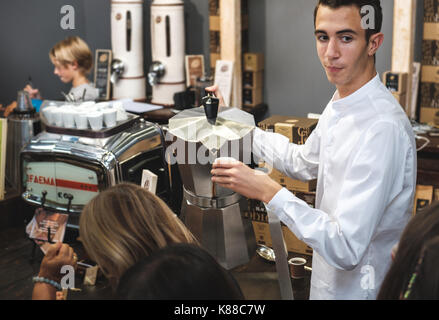 Caffe italiano au bar café italien, un jeune garçon italien habitudes Barista sert du café dans une cafetière moka géant Banque D'Images