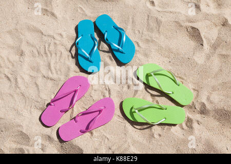 Paires colorées de tongs sur le sable Banque D'Images