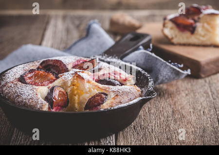 Tarte aux fruits d'été avec des prunes en fonte poêlon sur table en bois rustique Banque D'Images