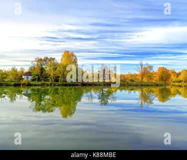 La maison de village, sur la rive du lac se reflète dans l'eau. forêt d'automne Banque D'Images