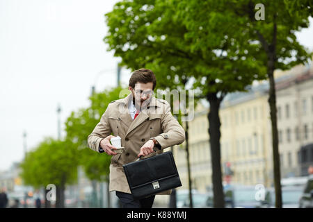 Homme d'affaires contemporain se déplaçant le long de rue et à la recherche au watch Banque D'Images