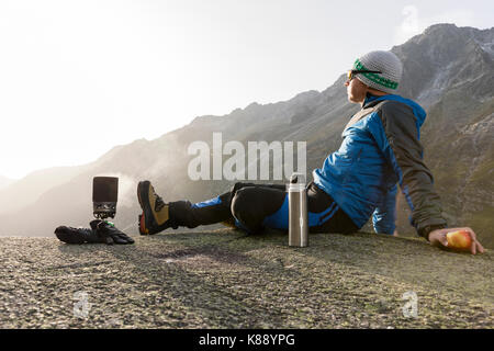 Alpinist fait une pause dans les montagnes, les cuisiniers plateau et bénéficie de l'aube Banque D'Images