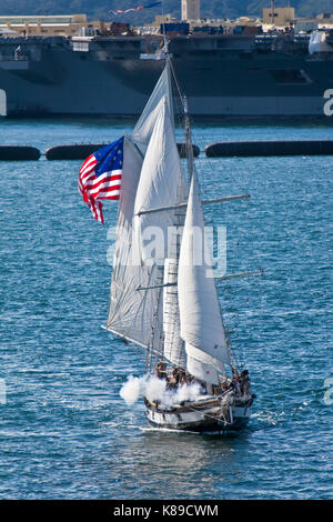 Grand voilier anazing grace toutes voiles dehors sur la baie de San Diego, CA US canons incendies au cours de bataille navale avec le porte-avions Formidable en arrière-plan Banque D'Images