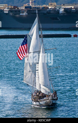 Grand voilier anazing grace toutes voiles dehors sur la baie de San Diego, CA US canons incendies au cours de bataille navale avec le porte-avions Formidable en arrière-plan Banque D'Images