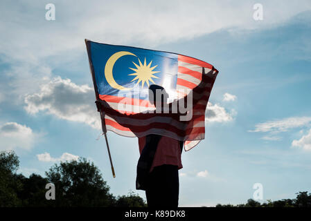 Silhouette d'un garçon tenant le drapeau malaisien célébrant la journée de l'indépendance de la Malaisie Banque D'Images