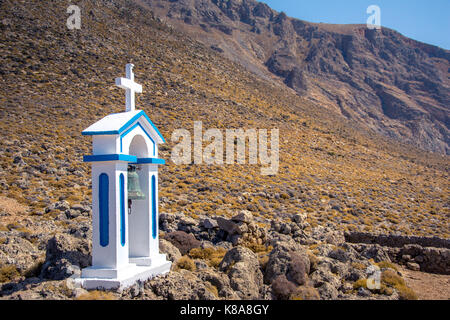 White clocher d'une église à côté de la mer bleue, à une journée ensoleillée, Loutro, Chania, Crète, Grèce. Banque D'Images