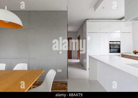 Table en bois et chaises blanches debout dans villa de luxe intérieur avec cuisine ouverte Banque D'Images