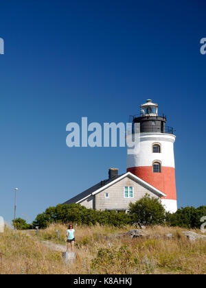 Femme marchant devant le phare de Söderarm, à l'extérieur de Räfsnäs, Gräddö, Rådmansö dans l'archipel de Roslagen, Stockholm, Suède. Banque D'Images