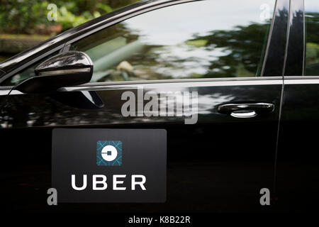 Une Volkswagen noire avec le logo Uber est utilisé comme un taxi et montre également un pilote dans une rue de banlieue verdoyante au Royaume-Uni (usage éditorial uniquement). Banque D'Images