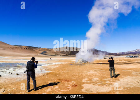 Touristes photographiant un fumarale à vapeur à la zone géothermique de Námafjall Hverir, Islande Banque D'Images