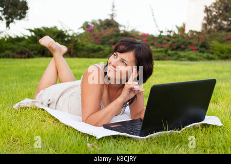 Jeune femme utilisant un ordinateur portable au parc Banque D'Images