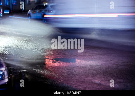 Voitures floue en mouvement. phares rouge réfléchissant sur route inondé lors de fortes pluies. Banque D'Images