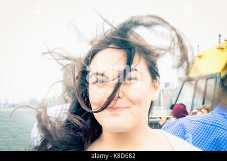 Gros plan d'une jeune femme à bord d'un Ferry de New York avec ses cheveux pour créer le vent tourne. Banque D'Images