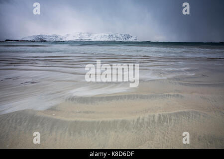 Les vagues sur la plage de sable modelées par le vent à l'arrière-plan les sommets enneigés ramberg lofoten, Norvège europe Banque D'Images