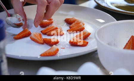 Fraises fraîches mis sur une assiette. femme met les fraises tranchées sur une plaque Banque D'Images