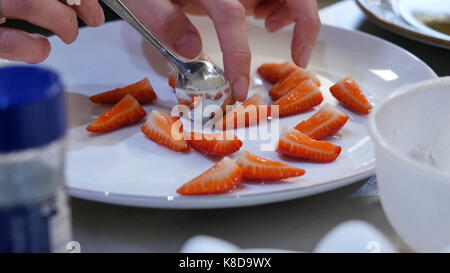 Fraises fraîches mis sur une assiette. femme met les fraises tranchées sur une plaque Banque D'Images