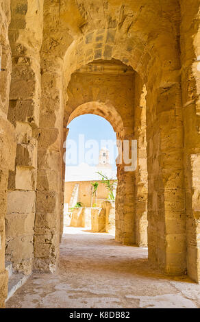 El Djem, Tunisie - septembre 1, 2015 : la vue sur la mosquée Blanche à travers l'arche du portique d'El Jem amphitheater, le 1 septembre à El Djem. Banque D'Images