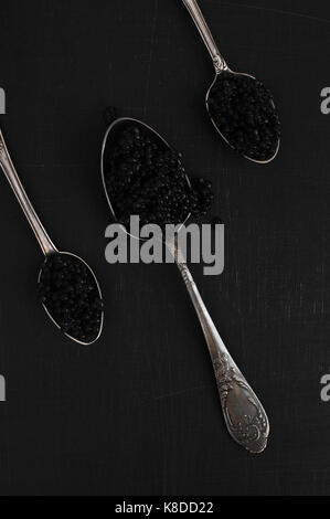 Black caviar dans les cuillères en argent sur le tableau noir Banque D'Images