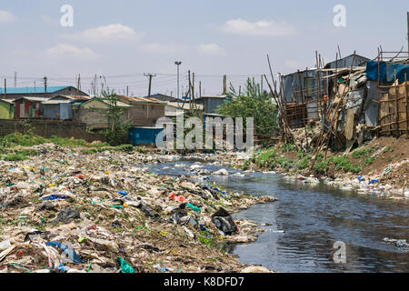 La ligne des baraques taudis rivière Ngong qui est polluée par des déchets, les déchets plastiques et les ordures, Nairobi, Kenya Banque D'Images