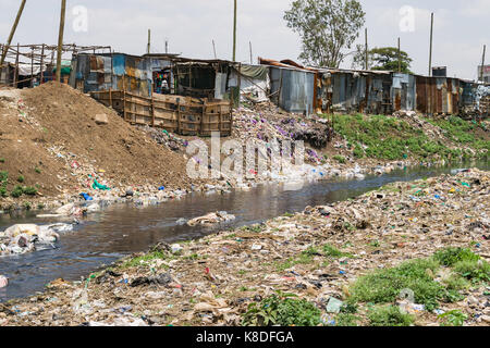 La ligne des baraques taudis rivière Ngong qui est polluée par des déchets, les déchets plastiques et les ordures, Nairobi, Kenya Banque D'Images