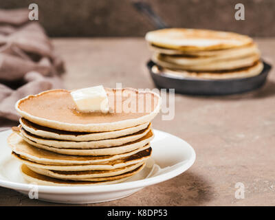 Vue rapprochée de crêpes maison. Pile de crêpes avec du beurre sur fond de béton brun. Banque D'Images