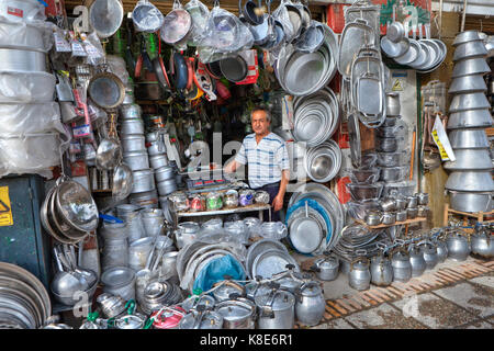 La province du Fars, Shiraz, Iran - 18 avril, 2017 Boutique : accessoires de cuisine en métal, un commerçant entouré par des marmites d'aluminium. Banque D'Images