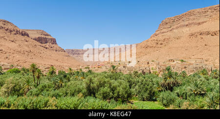 L'argile marocaine village perché entre les montagnes avec orange oasis de palmiers en face, le Maroc, l'Afrique du Nord. Banque D'Images