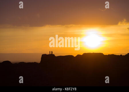 Deux personnes debout sur une crête de montagne lointaine silhouette par un grand soleil couchant juste au-dessus de l'horizon dans le désert de Gobi de Mongolie Banque D'Images