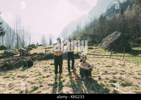 Quatre amis adultes regardant homme bouldering à partir de la vallée, Lombardie, Italie Banque D'Images