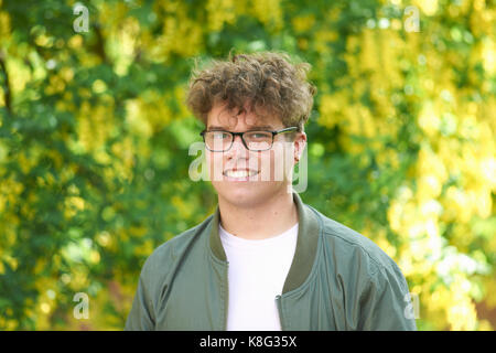 Portrait de jeune homme aux cheveux bouclés à la caméra en souriant Banque D'Images