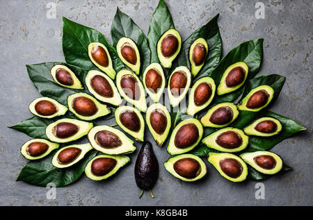 Peacock a fait de l'avocat palta et avocat, les feuilles des arbres autour de la plaque noire. Guacamole ingrédients. Gras sain, omega 3. La moitié d'avocat. Vue d'en haut Banque D'Images