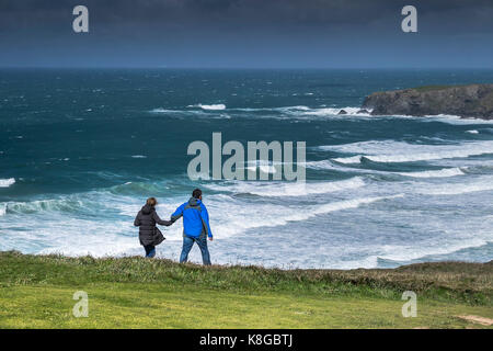 Bedruthan Steps - un couple marche main dans la main sur une falaise au chemin Bedruthan Steps sur la côte nord des Cornouailles. Banque D'Images